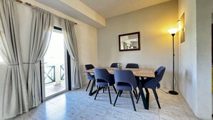 A dining area with a table and chairs, a large window with curtains, a floor lamp, and a mirror on the wall. - Entire Villa with Pool, Ocean View & A/C - 5min to beach and Culpepper Spring (St. Philip)
