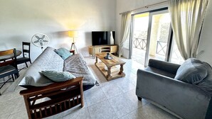 A living room with a sofa, armchair, wooden coffee table, and a TV. - Entire Villa with Pool, Ocean View & A/C - 5min to beach and Culpepper Spring (St. Philip)