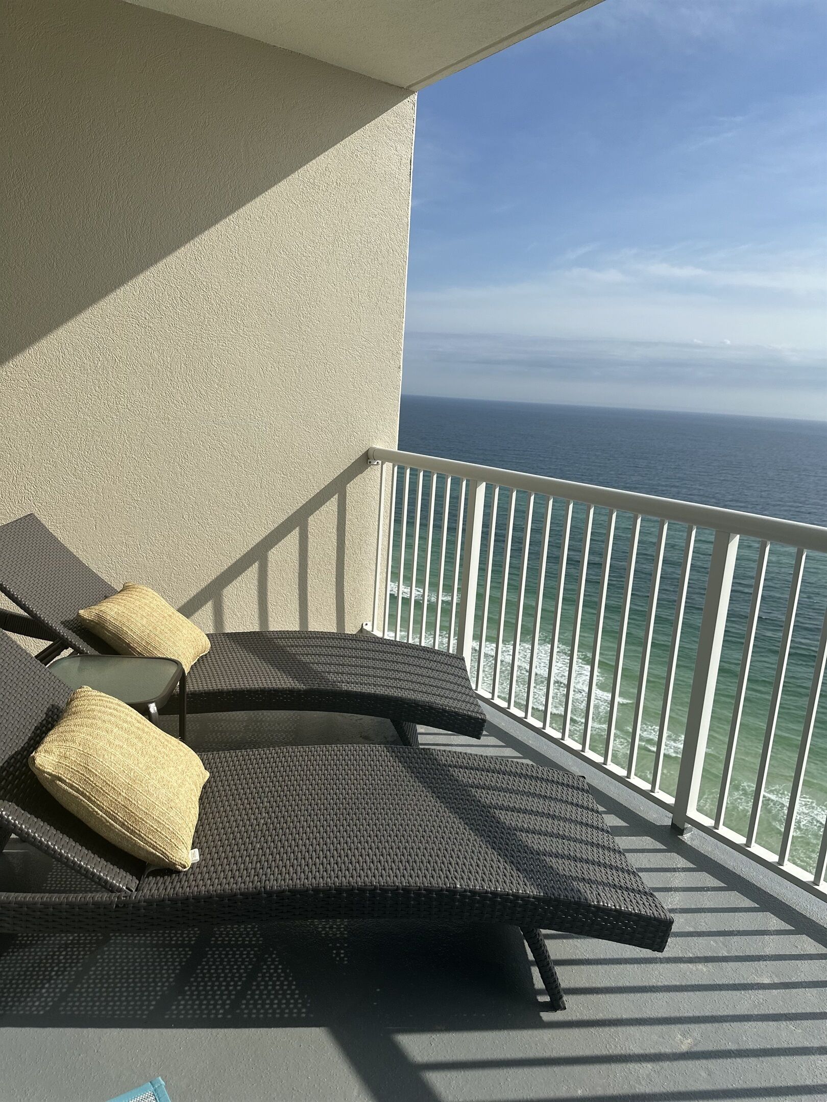 Ein Balkon mit zwei Korbstühlen, jeweils mit Kissen, mit Blick auf den Ozean.