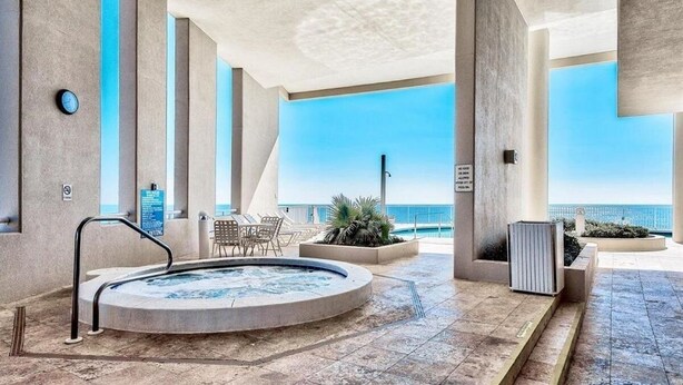 Ett modernt inomhuspoolområde med bubbelpool, sittplatser och utsikt över havet.