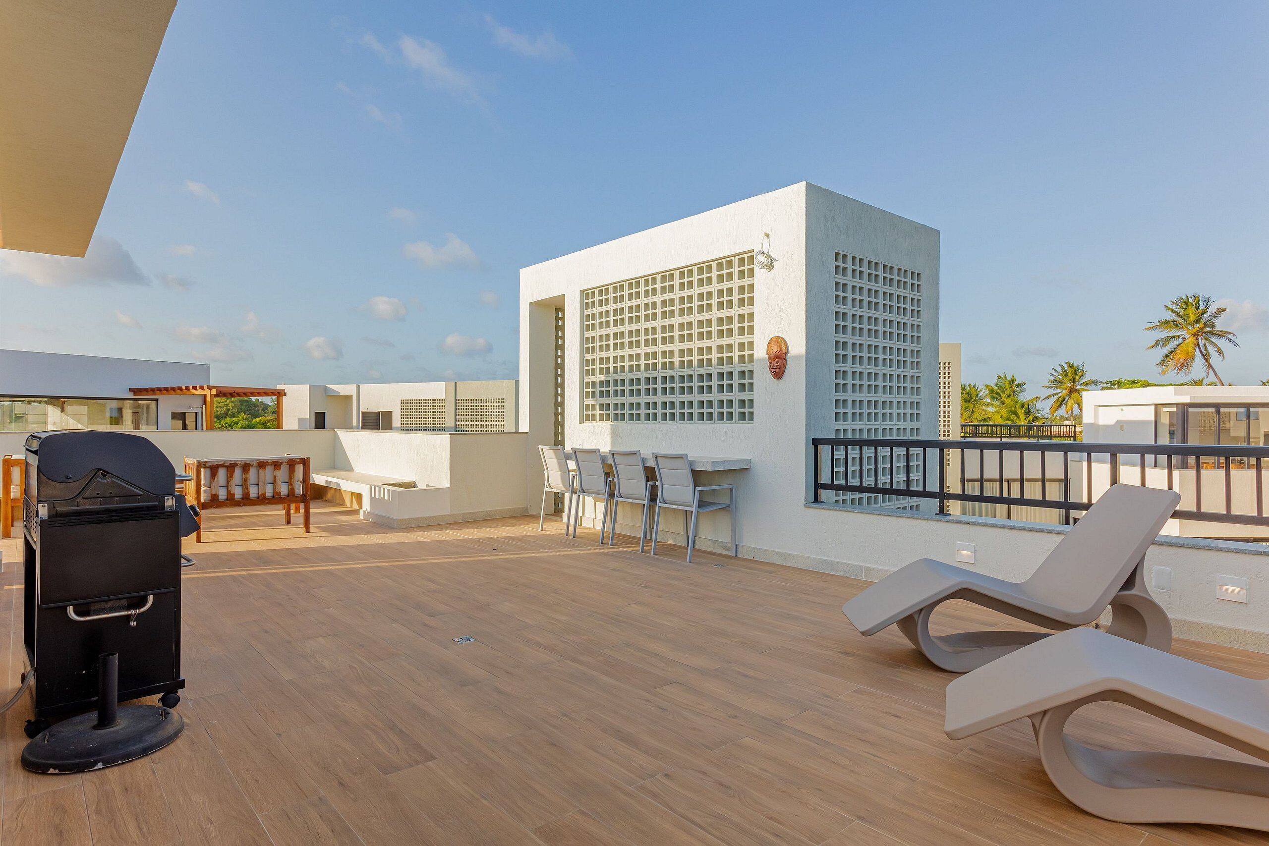A rooftop terrace with a grill, lounge chairs, and a dining area.