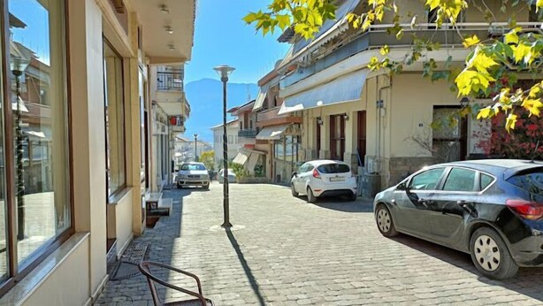 A cobblestone street with parked cars and buildings on either side. - Deluxe Family Suite - Kalabaka (Kalabaka)