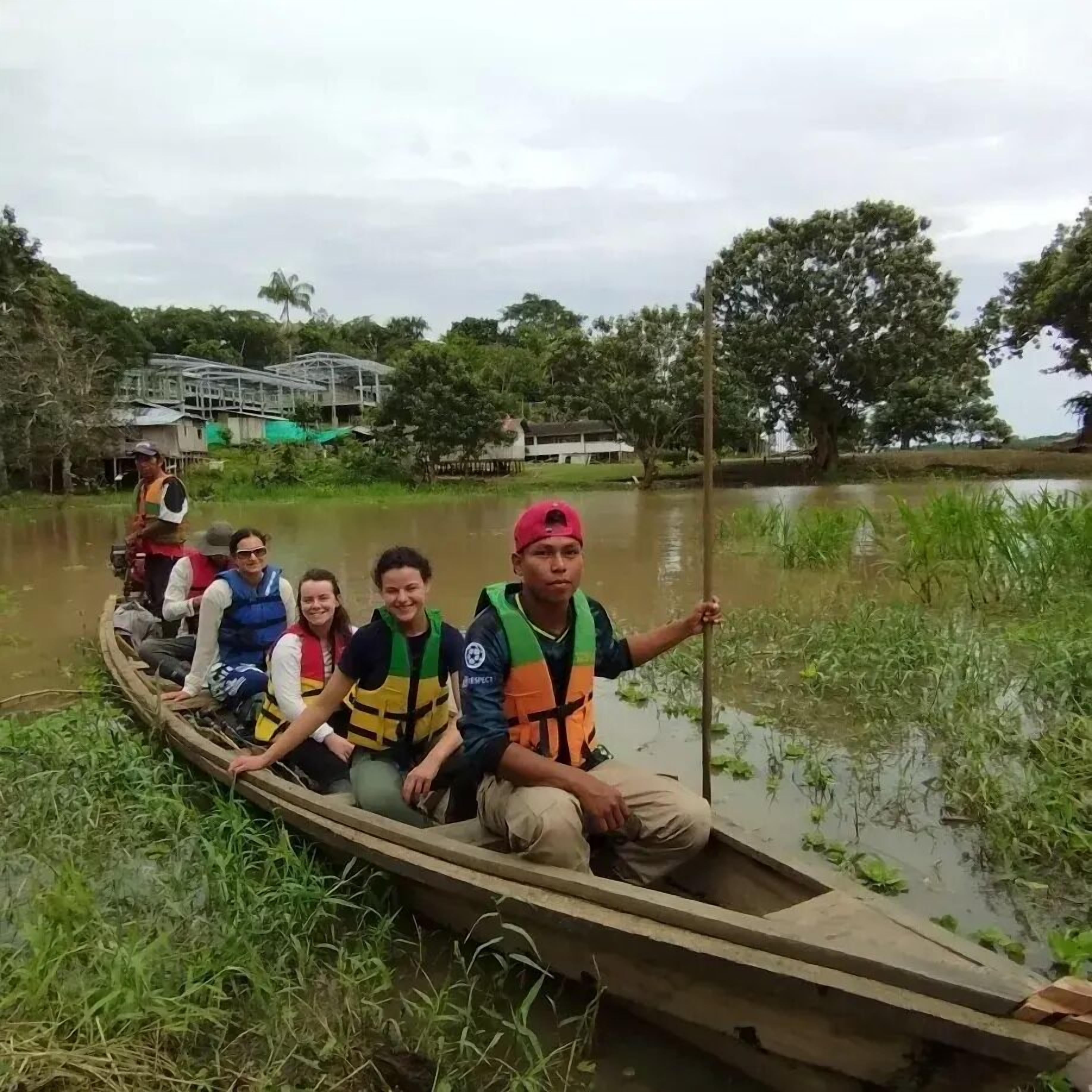 A group of people in a wooden boat on a river.