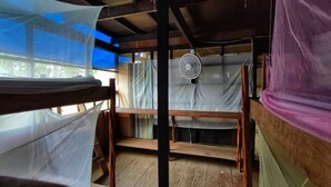 A room with wooden bunk beds, a ceiling fan, and a window covered with a white sheet. - Hospedaje  Reina Arriera Amazonas  (Leticia)