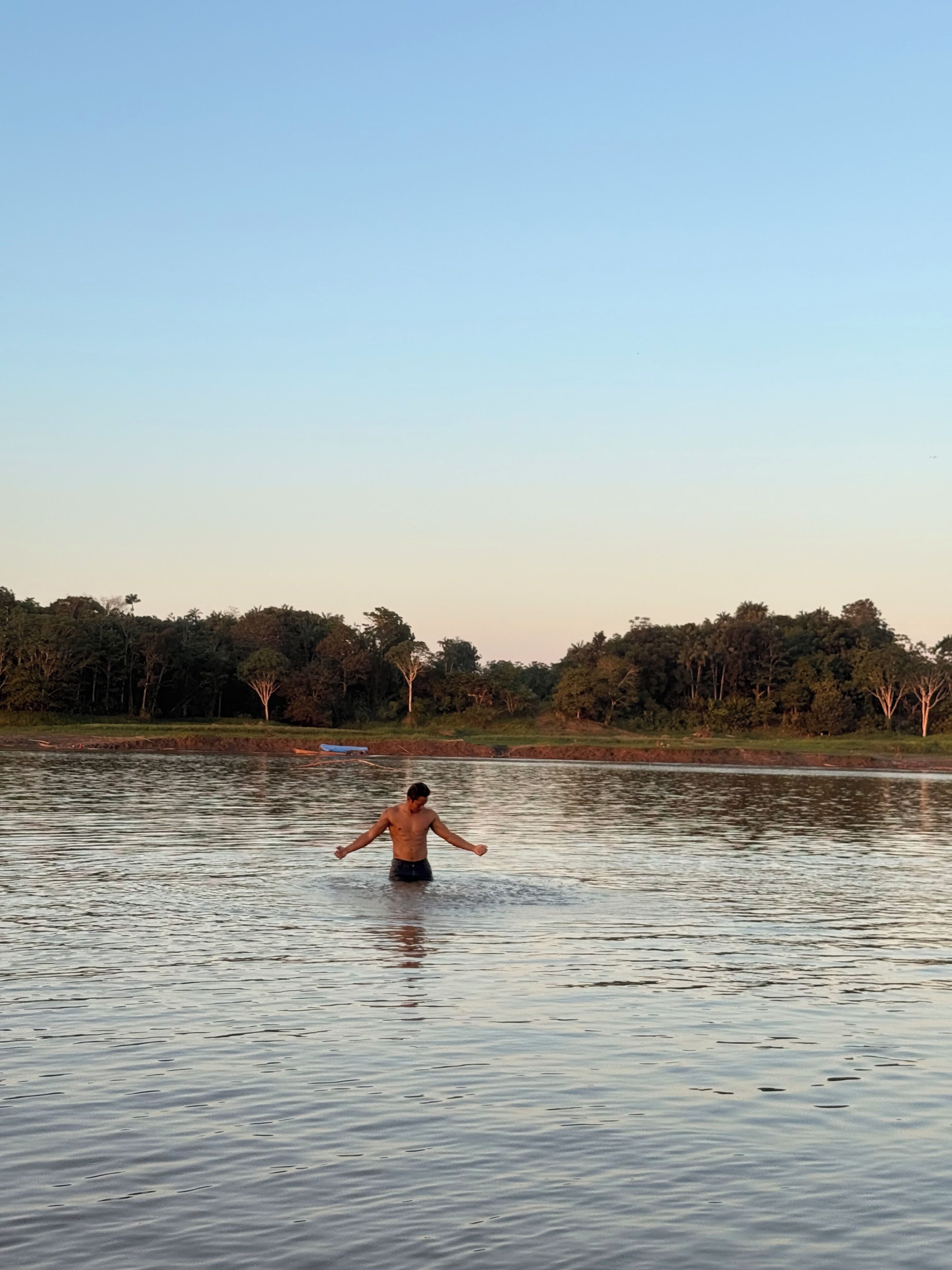 A person standing in a body of water with trees in the background.