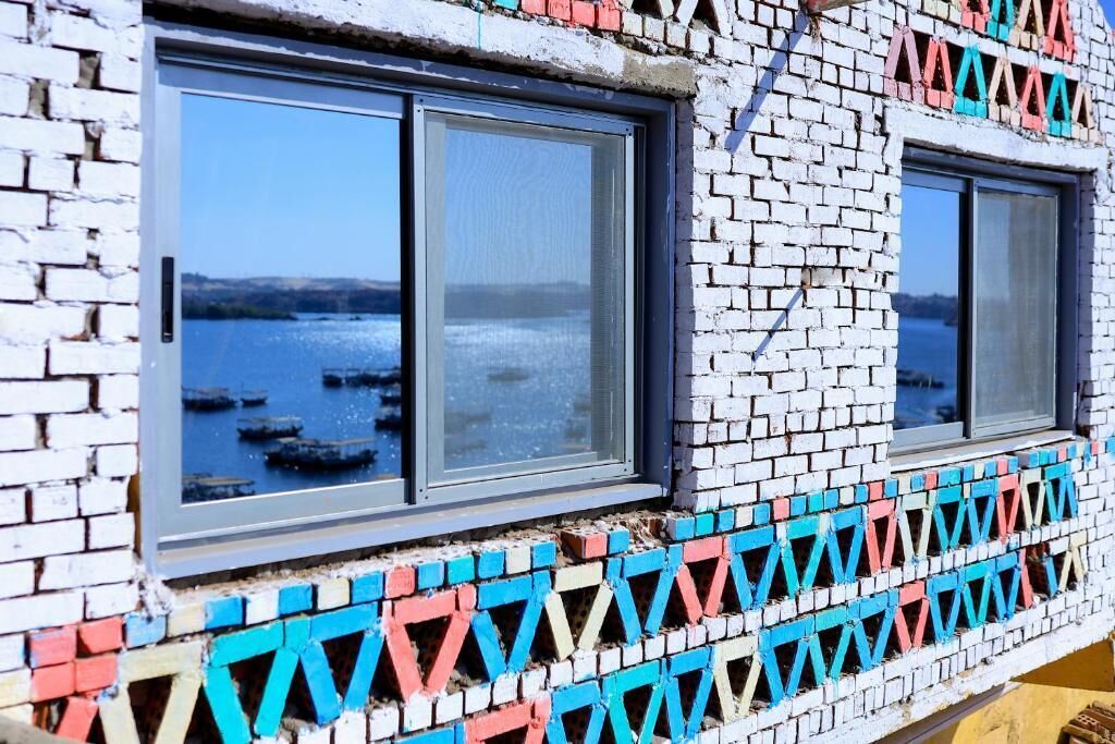 A building with two windows, a patterned brick facade, and a view of water.