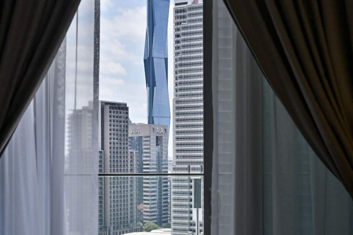 A hotel room with a large window offering a view of a cityscape, including a distinctive blue building.