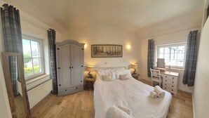 A bedroom with a bed, a wardrobe, a dresser, and a painting on the wall.