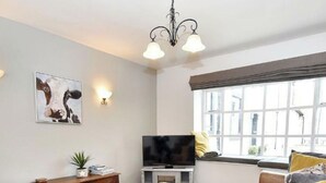 A living room with a television, sofa, coffee table, and a window with curtains.