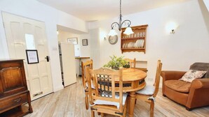 A dining area with a wooden table and chairs, a brown sofa, and a clock on the wall.
