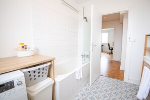A modern bathroom with a toilet, washing machine, and a sink with toiletries. - Le Tour(s) du Monde  - Joli appartement (Tours)