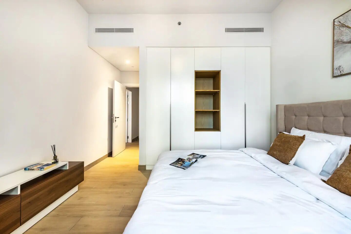 Un dormitorio moderno con una cama grande, armario empotrado y un rincón de lectura.