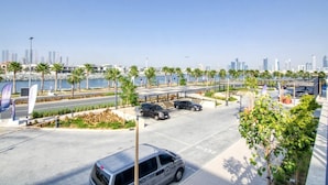 A parking area with a view of a city skyline, palm trees, and a body of water. - Stylish 2BR in La Rive 2 (Dubai)