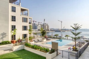 A rooftop pool area with a view of the sea, surrounded by modern buildings and construction cranes in the background. - Stylish 2BR in La Rive 2 (Dubai)