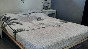 Une chambre à coucher comprenant un lit, une table de chevet, une fenêtre et des éléments de décoration murale, notamment un attrape-rêves et des papillons.