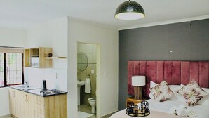 Una camera da letto moderna con un letto grande, un comodino con una lampada e vista sul bagno.