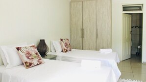 Habitación de hotel con dos camas, un armario grande y un baño visible a través de una puerta abierta.