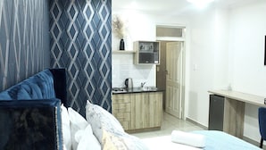 Una habitación de hotel compacta con cama, kitchenette pequeña y baño.