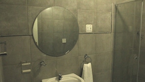 Un baño con un espejo redondo, un lavamanos y un perchero para toallas.