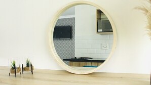 Een ronde spiegel aan de muur, met in de weerspiegeling een keuken, inclusief een magnetron en een betegelde spatwand.