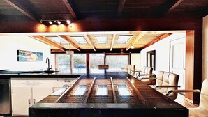 A spacious kitchen with a large island, wooden ceiling beams, and a view of the outdoors.