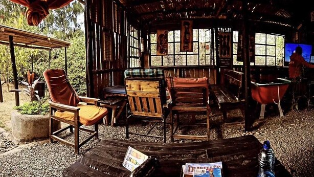 Un espacio de estar al aire libre con muebles de madera y una mesa donde se exhibe una revista.