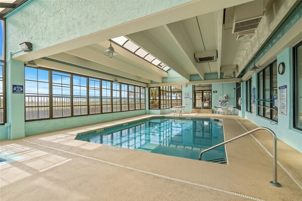 An indoor swimming pool with clear windows, a ceiling fan, and a 'No Smoking' sign.