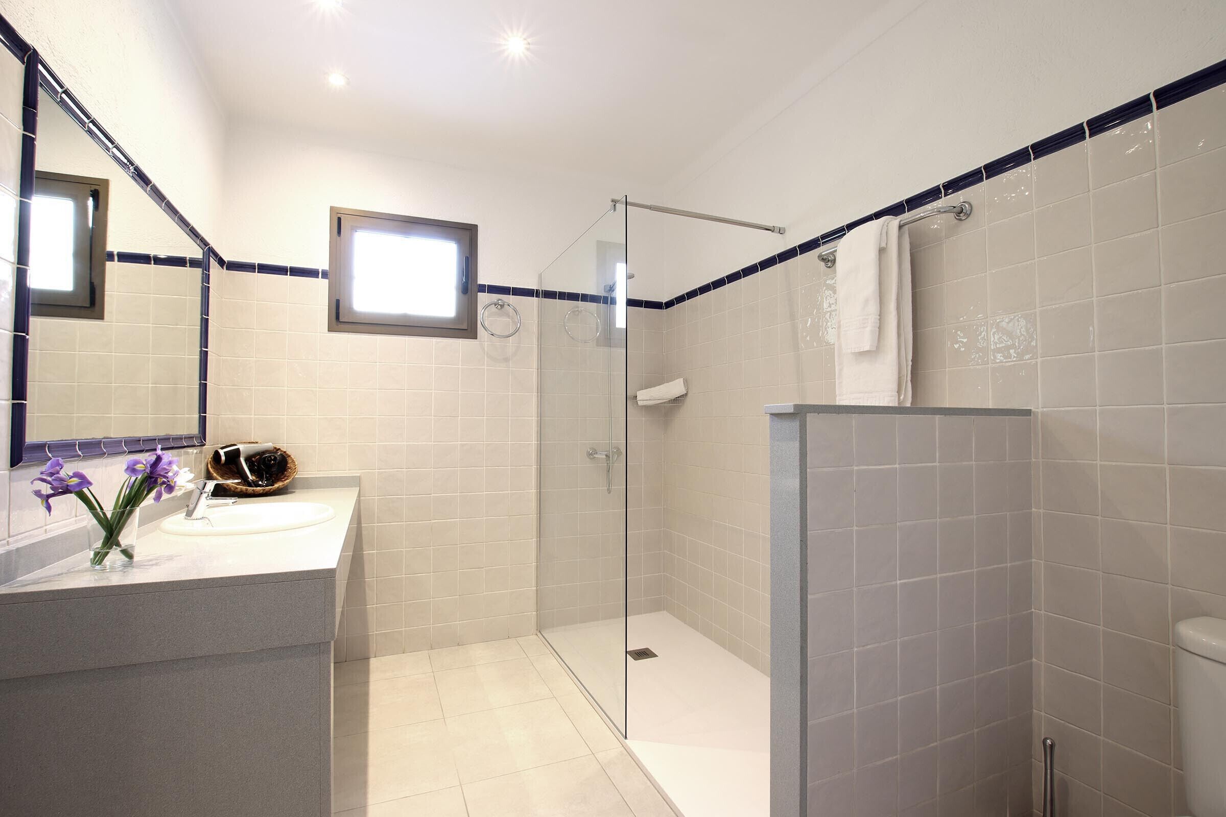 Een moderne badkamer met een douchecabine van glas, een wastafelmeubel en een spiegel.