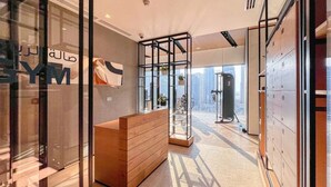 Un hall d’hôtel moderne avec un comptoir d’accueil, une cloison en verre et une vue sur le paysage urbain.