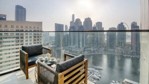 Un balcon avec vue sur la ville, comprenant une rivière et des bateaux, ainsi qu’une table avec une théière et des tasses.