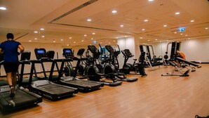 A gym with treadmills, elliptical machines, and weight equipment. - Green community 1BR 15 min to sea (Dubai)