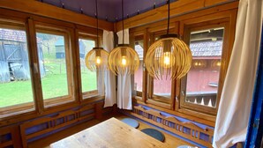 Ein Holzhütten-Interieur mit großen Fenstern, einem Holztisch und hängenden Pendelleuchten.