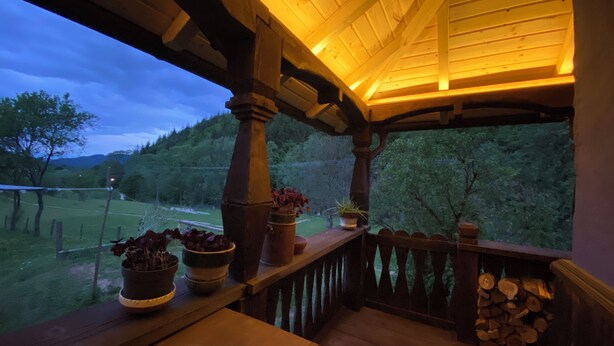 Eine hölzerne Veranda mit Blick auf eine grüne Landschaft und einen klaren Himmel.
