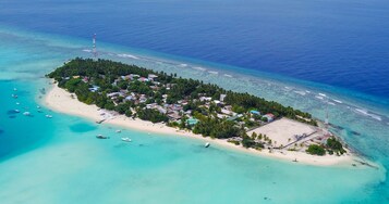 Vista aérea de una isla tropical con playa, embarcaciones y edificios.