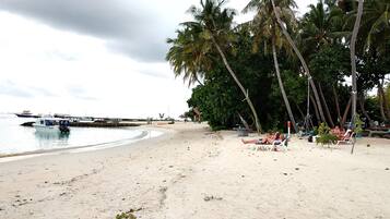 Una playa con palmeras, un barco y un muelle.