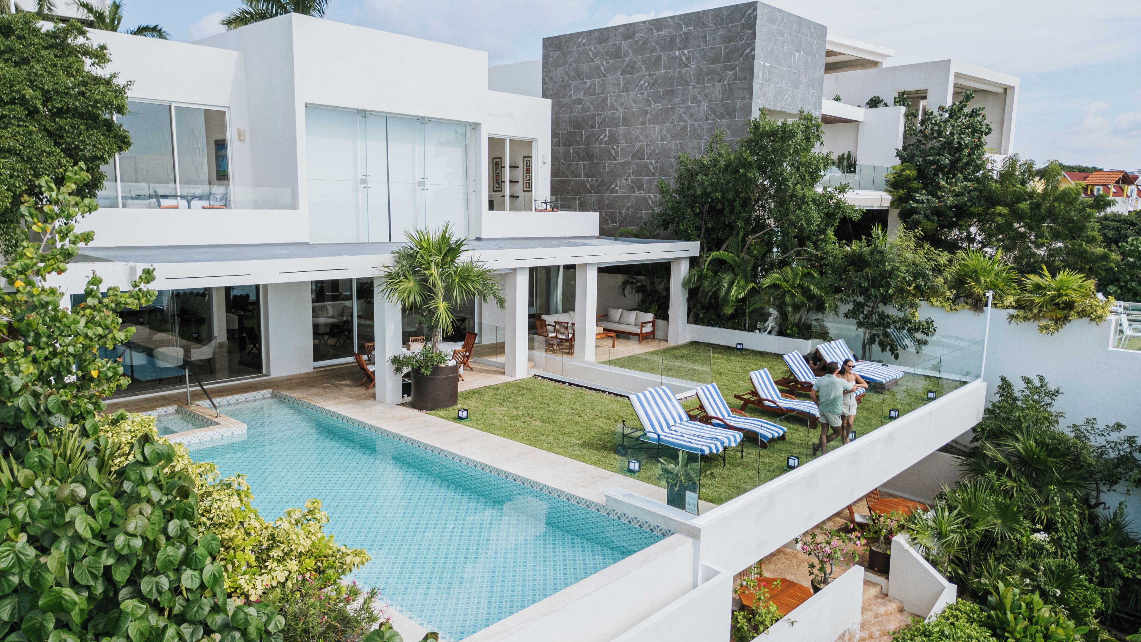 A modern house with a swimming pool, outdoor seating, and lush greenery.