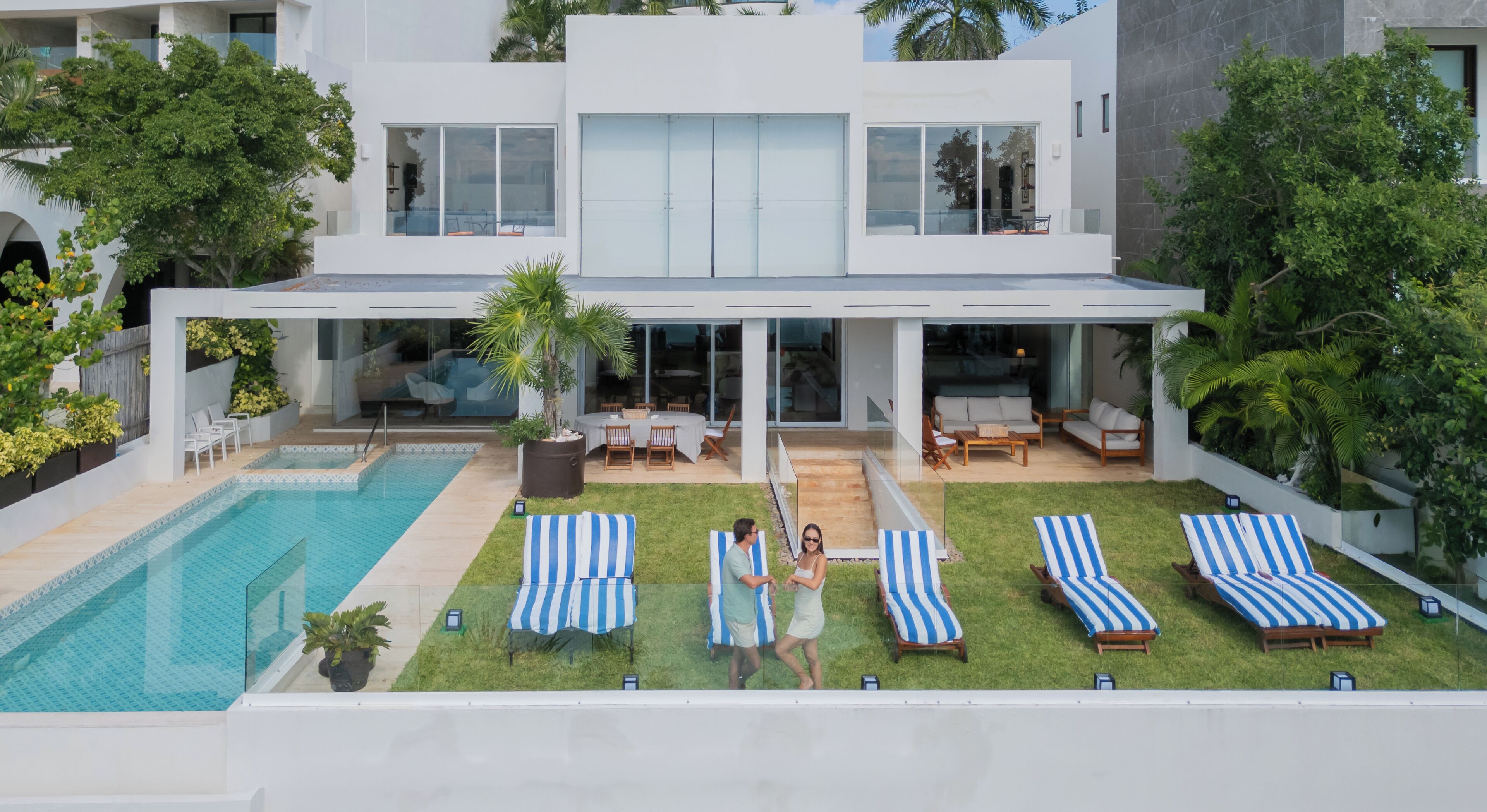 Ein modernes Haus mit Schwimmbad, Gartenmöbeln und einem gepflegten Rasen.