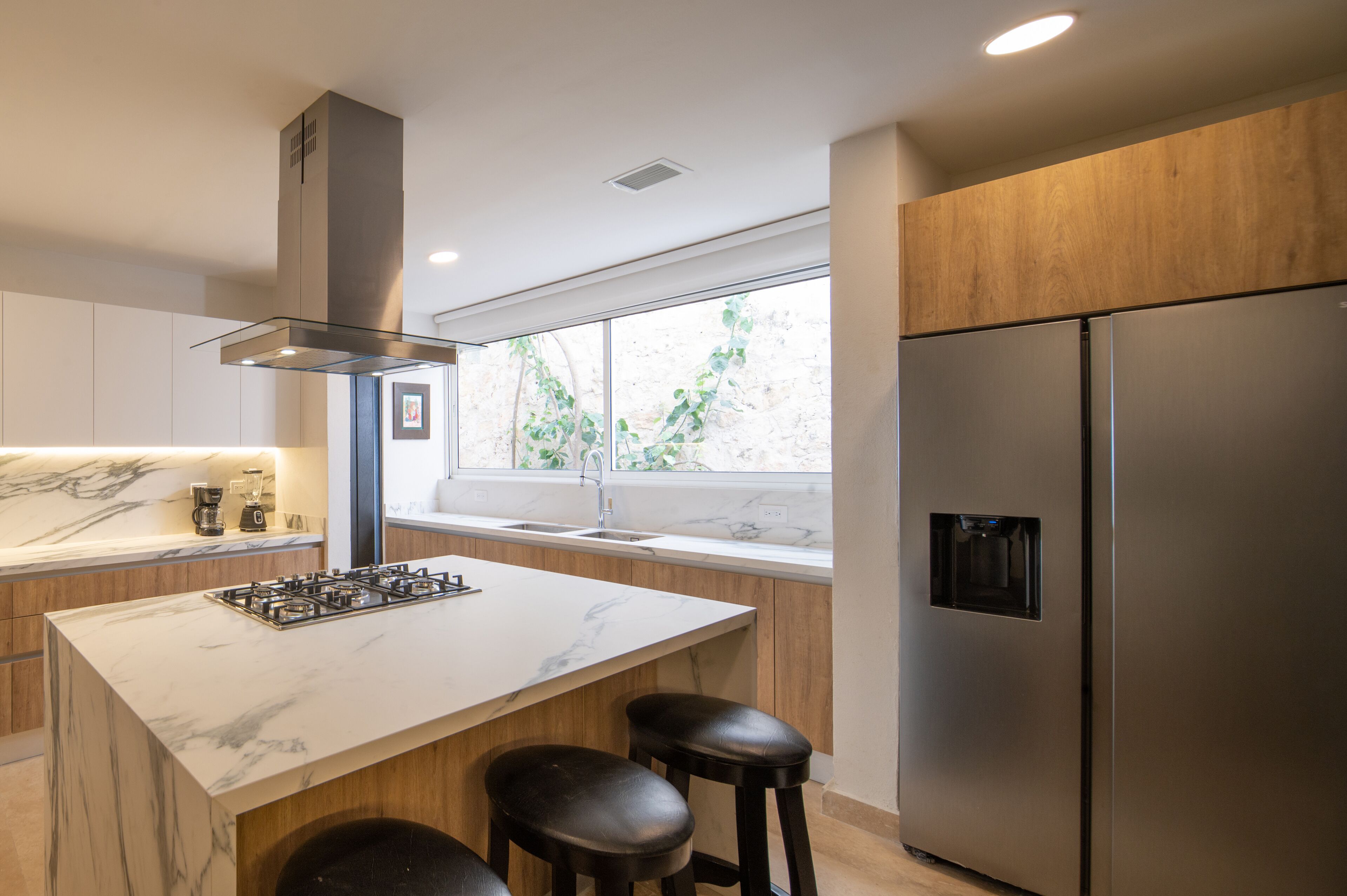 A modern kitchen with a marble countertop, stainless steel appliances, and wooden cabinets.