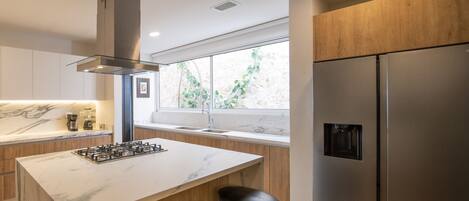 A modern kitchen with a marble countertop, stainless steel appliances, and wooden cabinets.