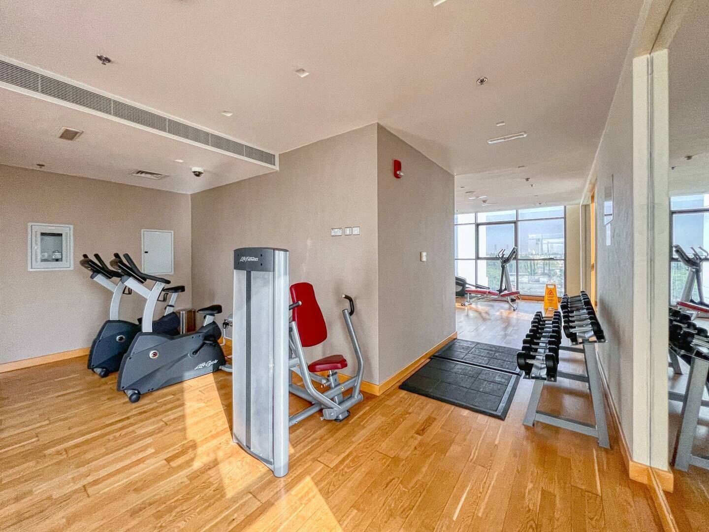 A gym with cardio machines, weight benches, and a red chair.