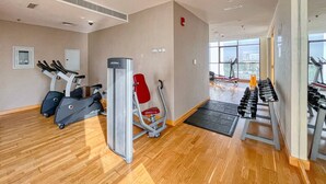 A gym with cardio machines, weight benches, and a red chair. - Cozy studio at Damac Hills (Dubai)