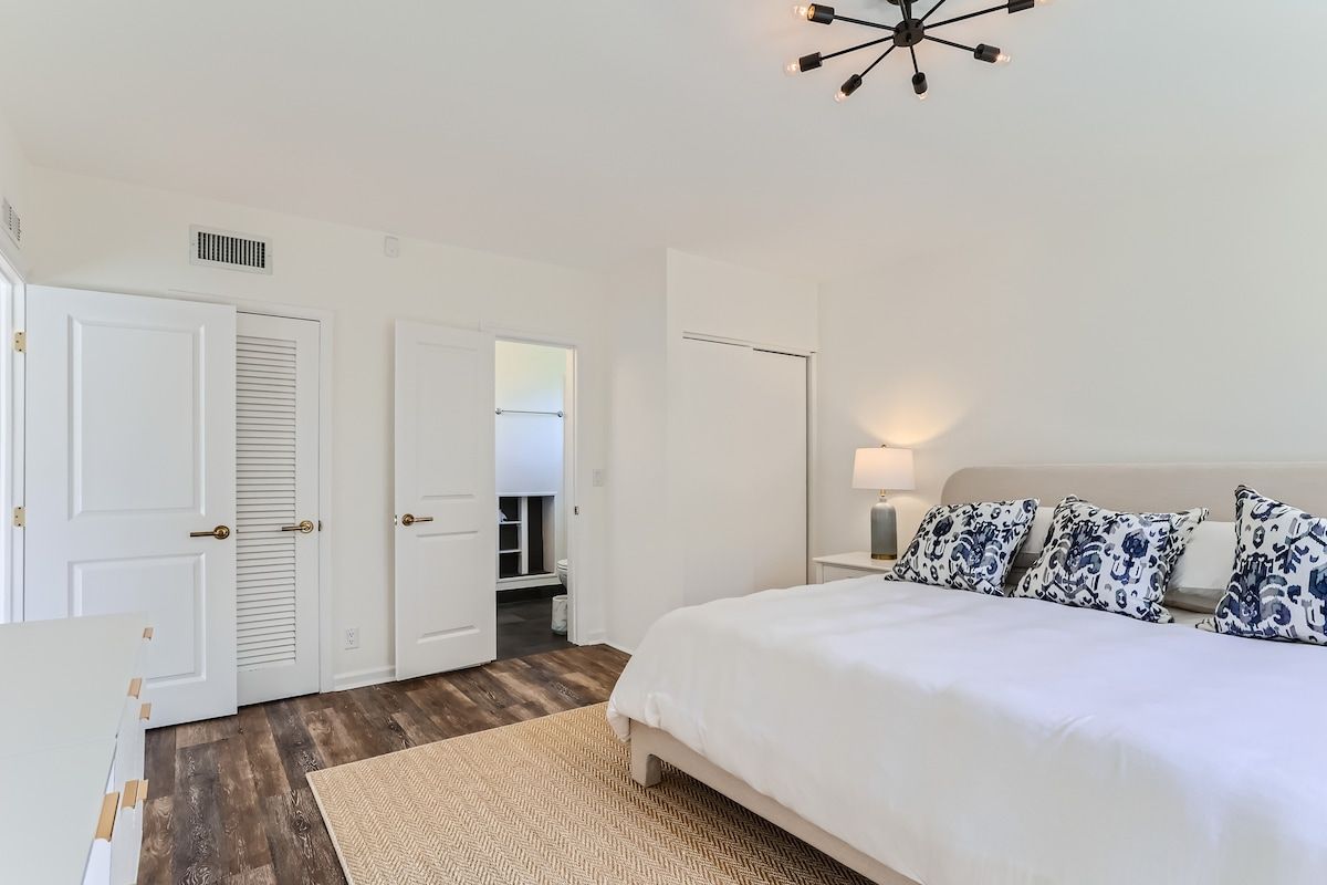 A bedroom with a bed, bedside tables, a lamp, and a ceiling light fixture.