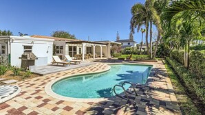 A pool area with a tiled deck, lounge chairs, and a barbecue grill. - The Glenn House - Gather Poolside in a Breezy South End Getaway (West Palm Beach)
