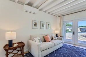 Sala de estar com sofá, duas mesinhas laterais e quadros nas paredes.