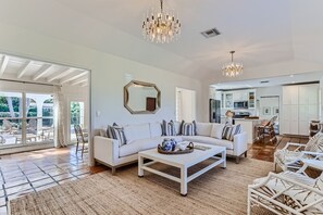 A spacious living room with a white sofa, a coffee table, and a chandelier.