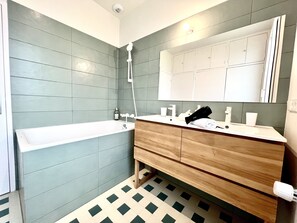 Un bagno moderno con una vasca, un mobile bagno in legno e uno specchio grande.