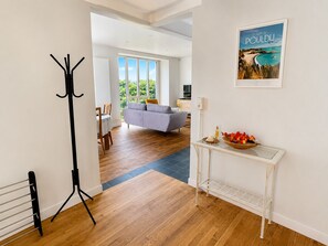 Una sala de estar moderna con un sofá, un comedor con mesa y sillas, y un perchero.