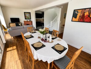 A dining area with a round table set for four, surrounded by wooden chairs.