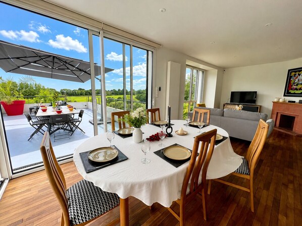 Un comedor con una mesa dispuesta para seis personas, ventanas amplias y vistas al exterior.