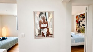Una camera da letto con un letto, un quadro appeso al muro e una porta che conduce in un'altra stanza.